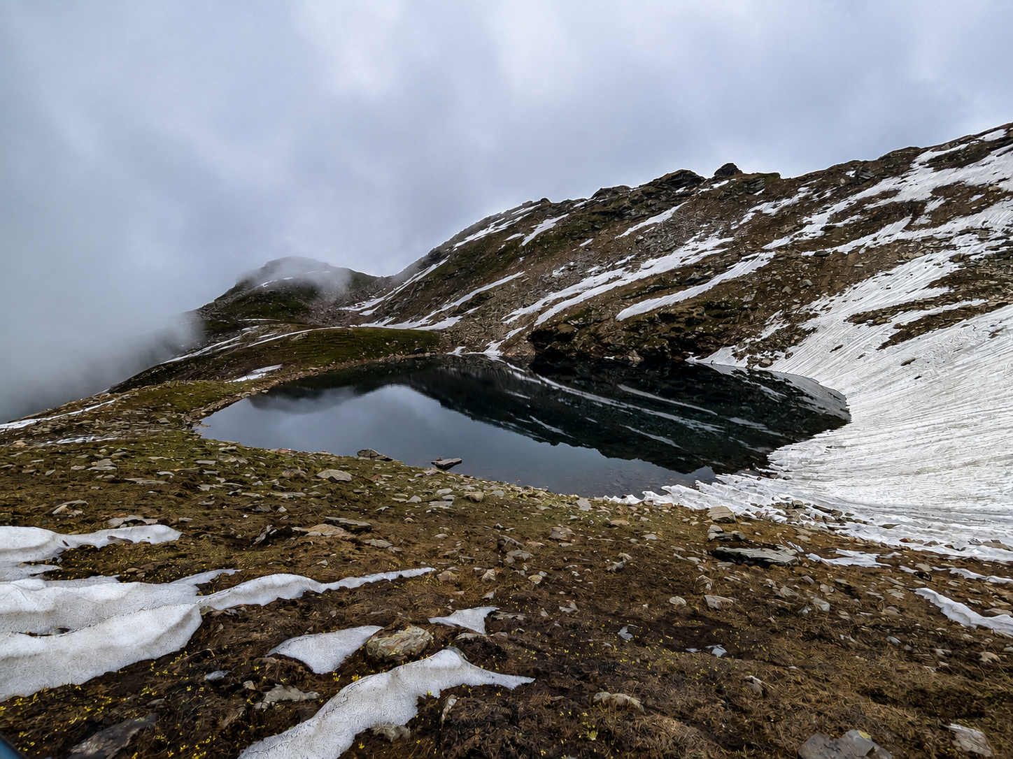Bhrigu Lake at 4,180 m with snow patches and high alpine slopes